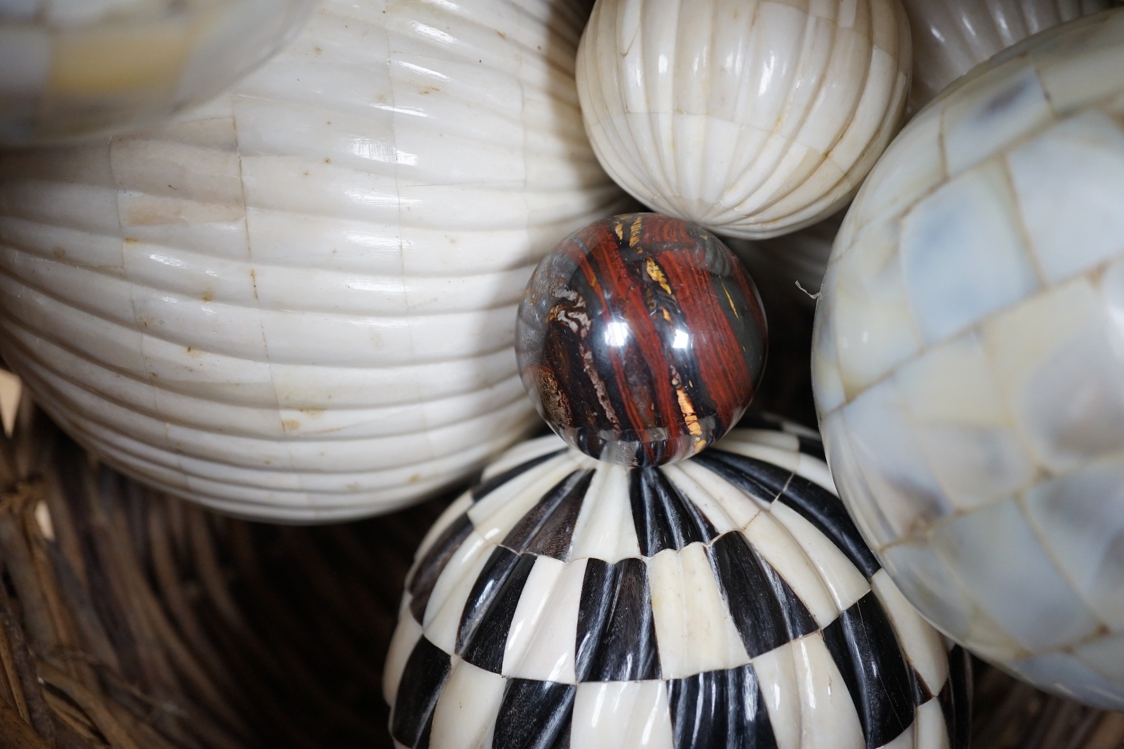 A basket of mother of pearl or bone veneered balls and other decorative balls